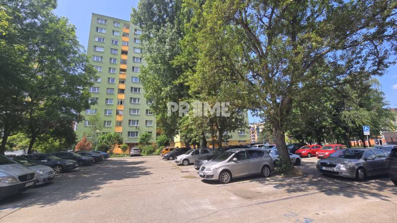 Parking lot in Bratislava - Petržalka on Osuského Street with a view of apartment buildings and greenery.