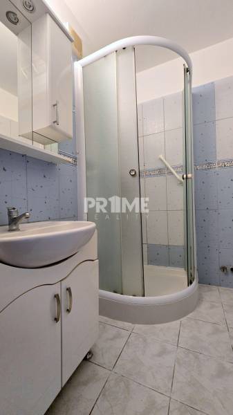 A bathroom in a 3-room apartment with a sink and a shower corner.