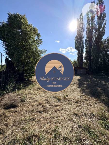 Sunny plot with trees, warehouses and halls in Marcelová, surrounded by nature and grassy area.