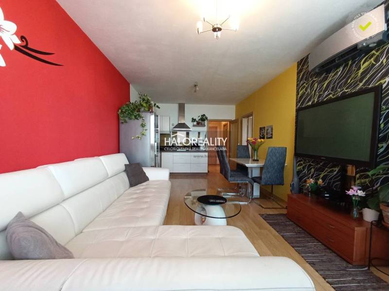 Living room with a white couch, decorative walls, and a dining table in a two-room apartment.