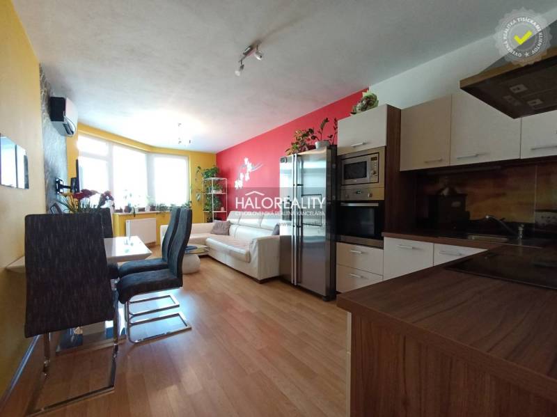 Living room with kitchen in a 2-room apartment, with light decor and a dining table.