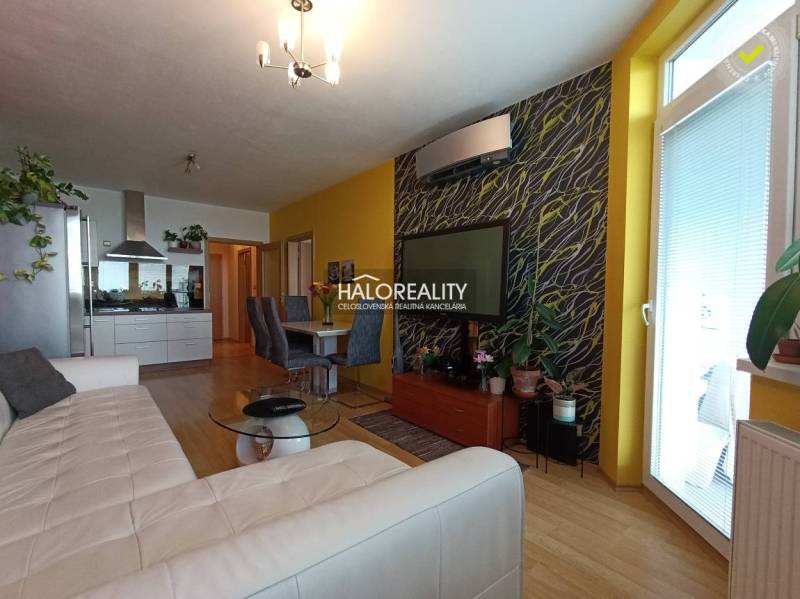 Living room with a kitchen in a 2-room apartment, with yellow walls and wooden flooring.