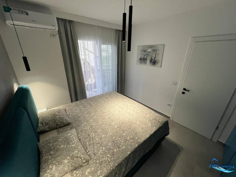 Recreational apartment with a comfortable bed, air conditioning, and balcony doors with a view.