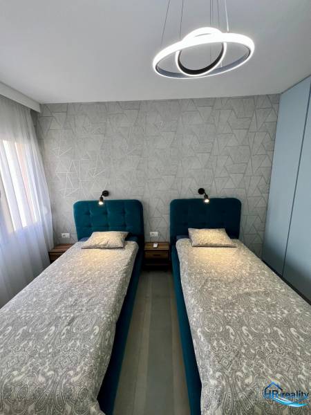 Double bedroom with geometric wallpaper and modern lighting in a holiday apartment.