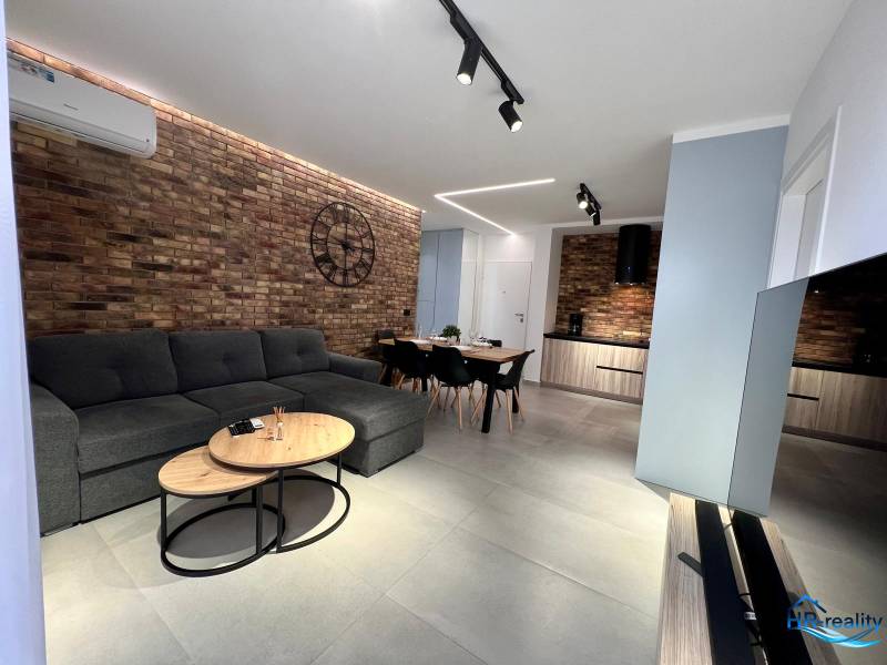 Living room in a holiday apartment with a brick wall, sofa, and television.