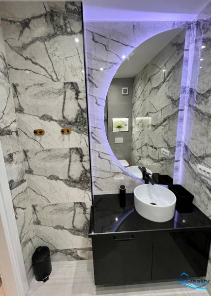 Bathroom in a holiday apartment with a round mirror and elegant tiles.