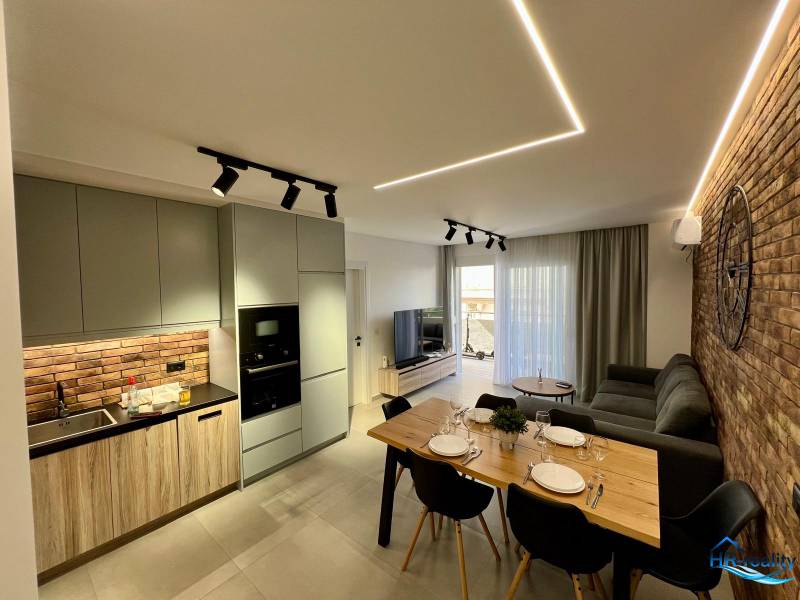 Living room with kitchen in a holiday apartment. Brick wall, dining table, and comfortable sofa.