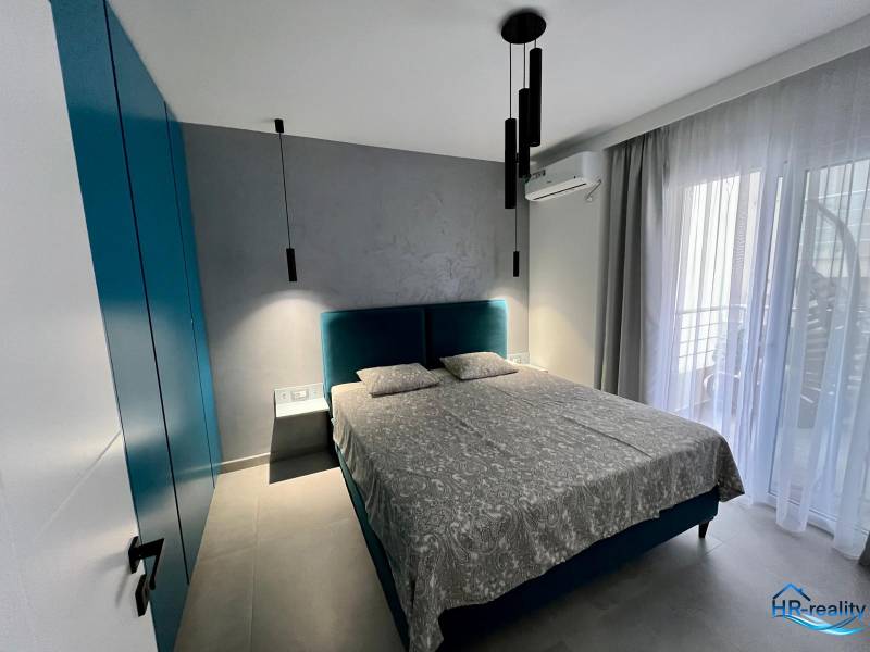 A room with a comfortable bed, a wardrobe, curtains, and balcony doors.