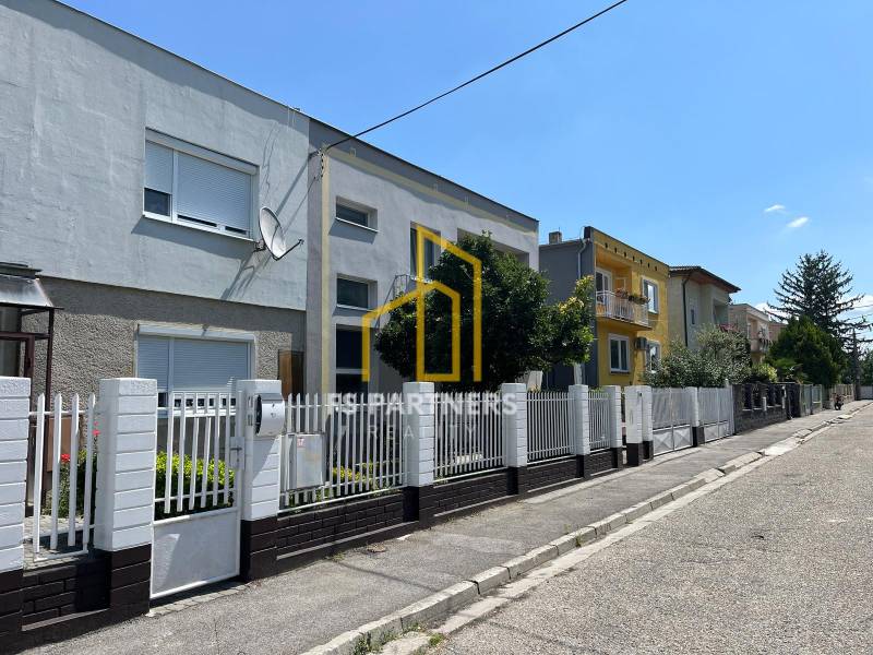 A street with family houses in Komárno, with a white fence and a satellite dish.