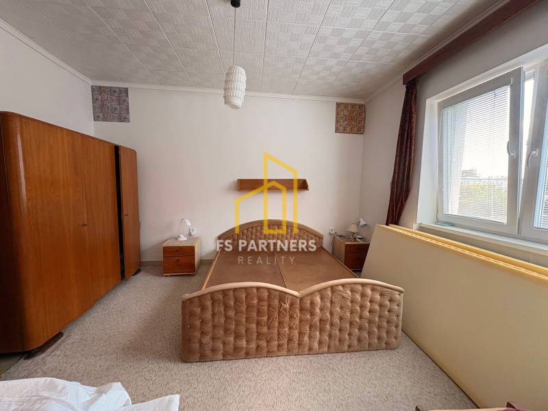 A bedroom in a family house with a large bed and wooden wardrobes.