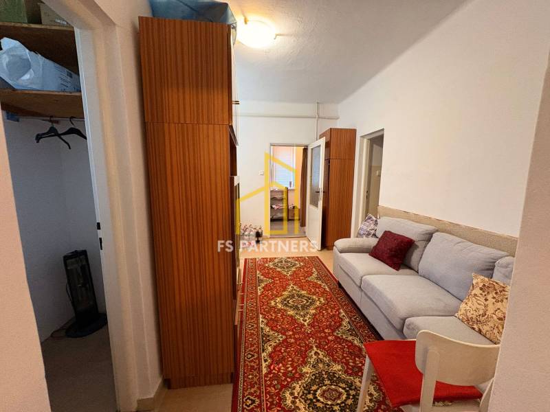 A hallway in a family house with a sofa, a wooden wardrobe, and a red carpet.