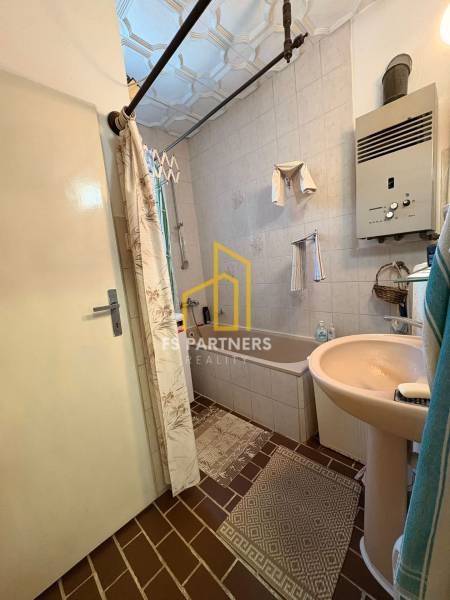 Bathroom in a family house with a bathtub, gas heater, and tiled floor.