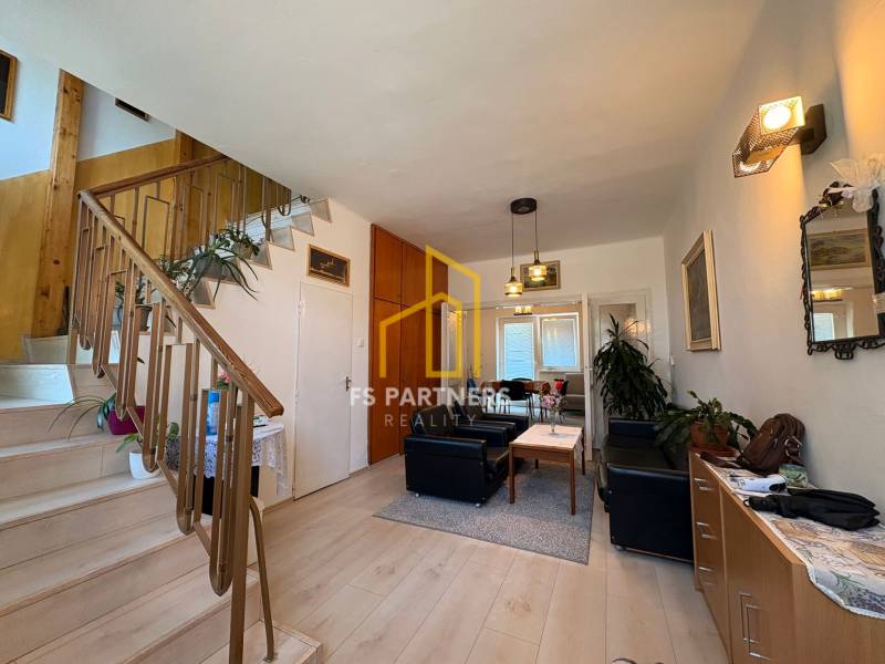Living room with a staircase in a family house, with seating and decorative elements.