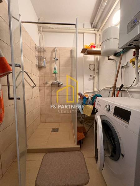 A bathroom with a washing machine and a shower in a family house.