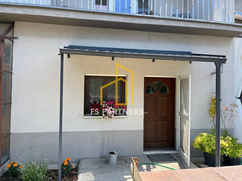 A family house in Komárno with a terrace and flowers in front of the entrance.