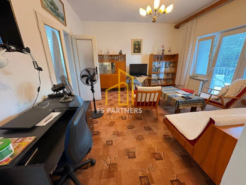 Living room in a family house with older furniture and a table fan.