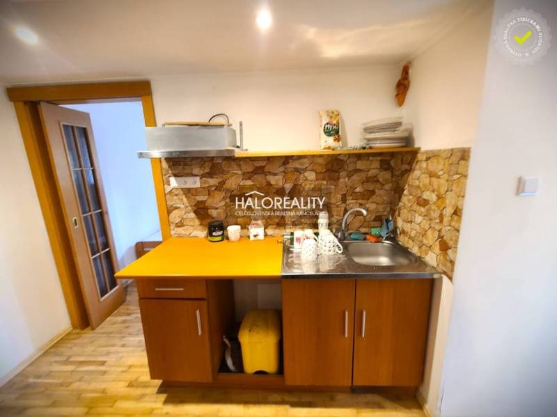 A kitchen in a family house with wooden furniture and stone cladding.