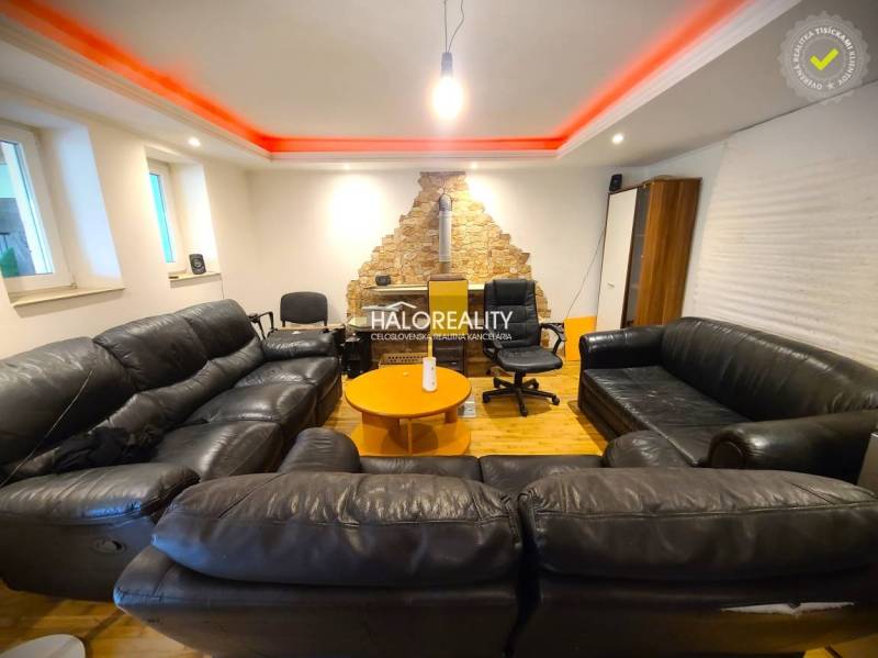 Living room in a family house with black sofas and a stone wall.