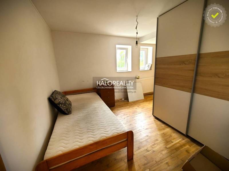 A room with a single bed, a wardrobe, and two windows in a family house.
