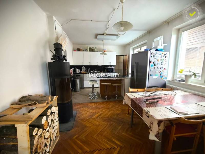 Family house kitchen with a stove, dining table, and refrigerator on a colorful floor.