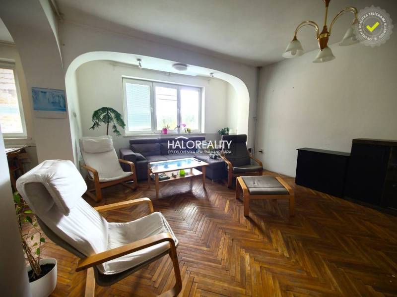 A living room in a family house with armchairs and a brown sofa.