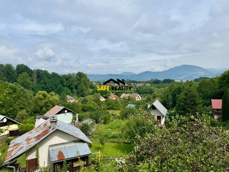 A country cottage in Mojš surrounded by greenery and hills under a blue sky.