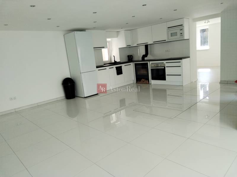 A kitchen in a family house with white furniture and ceramic flooring.