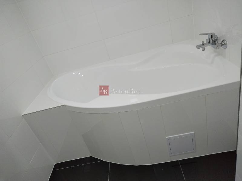 White bathtub with a faucet in the bathroom of a family house.