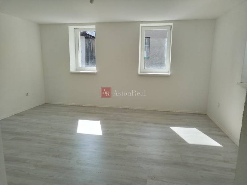 A bright room with two windows and laminate flooring in a family house.