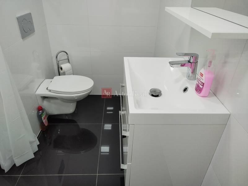 Bathroom in a family house with a toilet, sink, and white tiles.