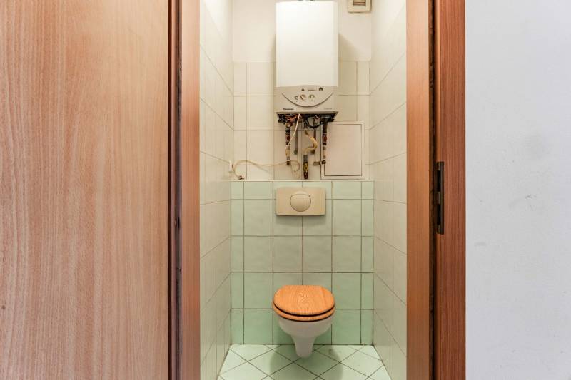 Bathroom with toilet and boiler in a 2-room apartment, tiled.