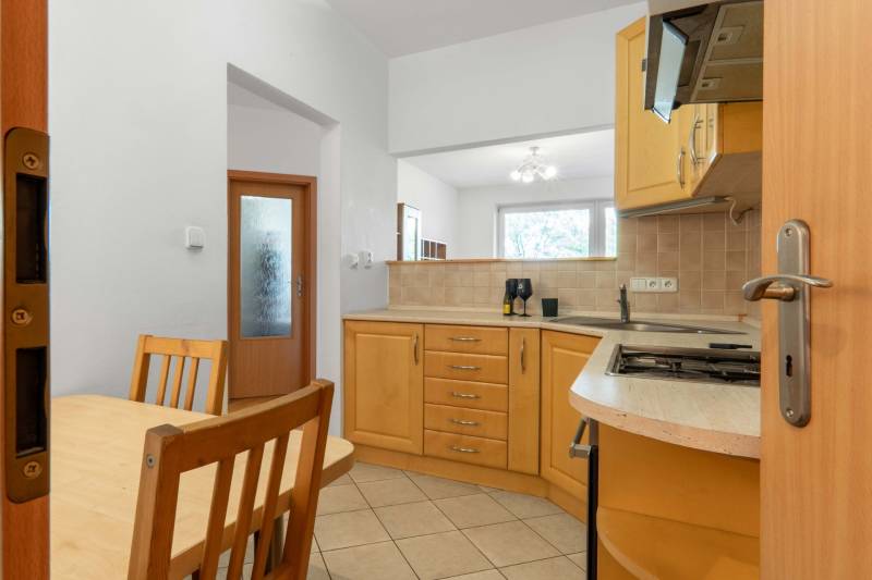 A kitchen in a 2-room apartment with wooden furniture and built-in appliances.