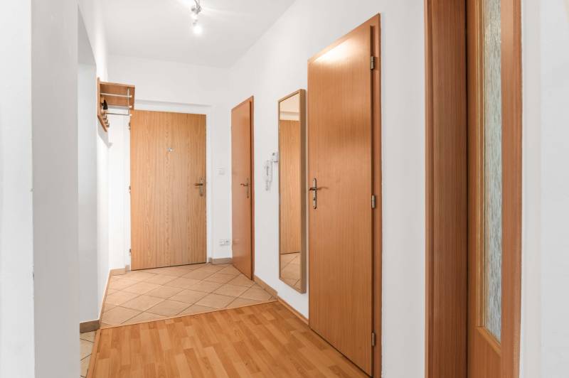 Entrance hall in a 2-room apartment with wooden doors and a mirror on the wall.