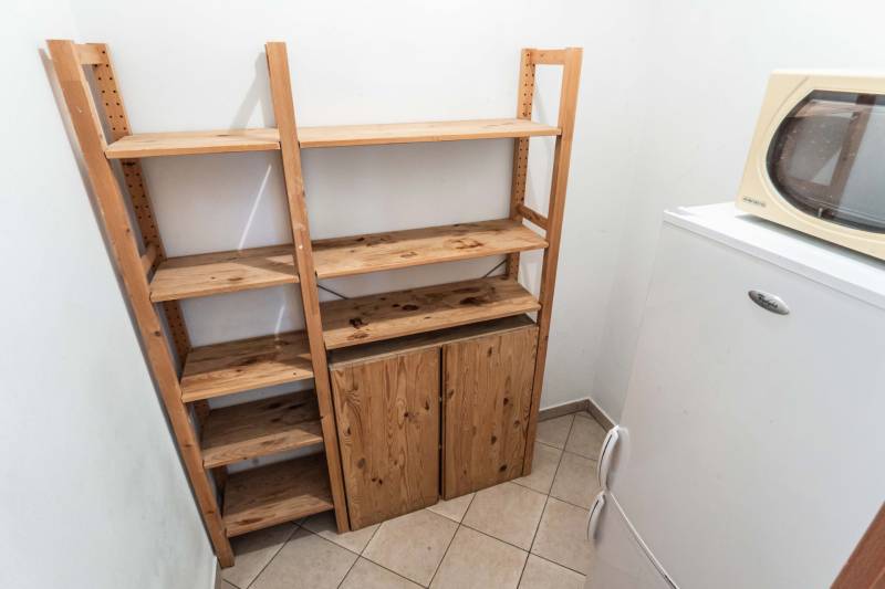 Wooden shelves next to the refrigerator and microwave in a 2-room apartment.