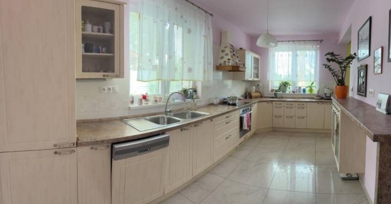 A spacious kitchen in a family house with wooden cabinets and many windows.
