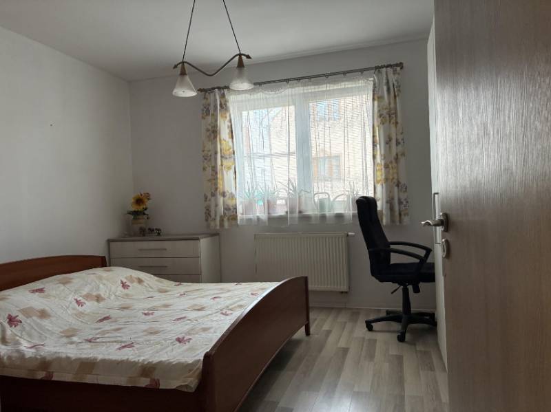 Bedroom with a bed, office chair, and dresser in a family house.