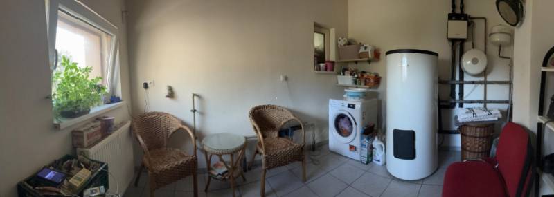 Laundry room in a family house with a washing machine, boiler, and wooden furniture.