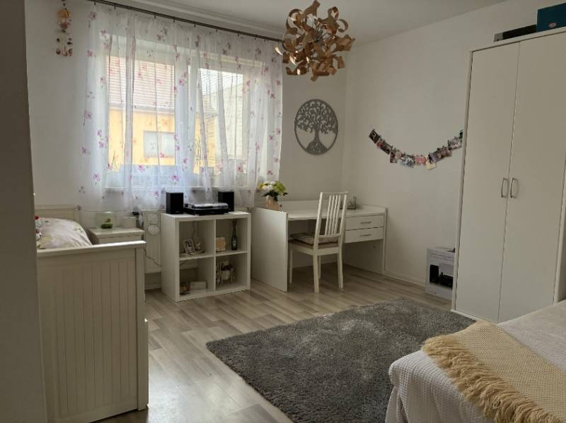 A bright room in a family house with white furniture, a desk, and decorations.