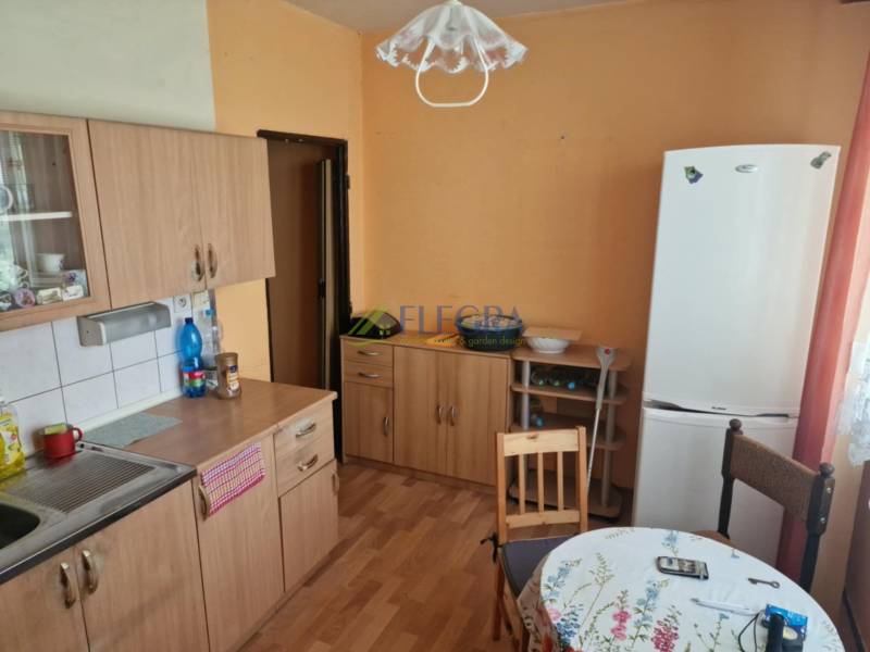 Kitchen in a studio apartment with wooden cabinets, a table, and a refrigerator.