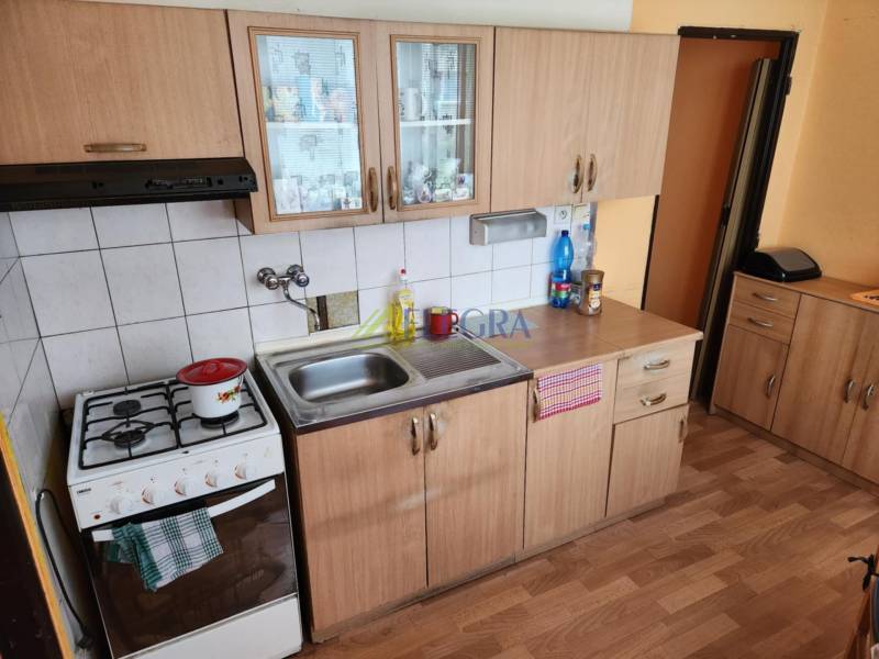 A kitchen in a studio apartment with wooden cabinets and a gas stove.