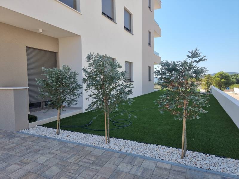 Exterior of a 4-room apartment in Vodice, elegant garden with trees and lawn.
