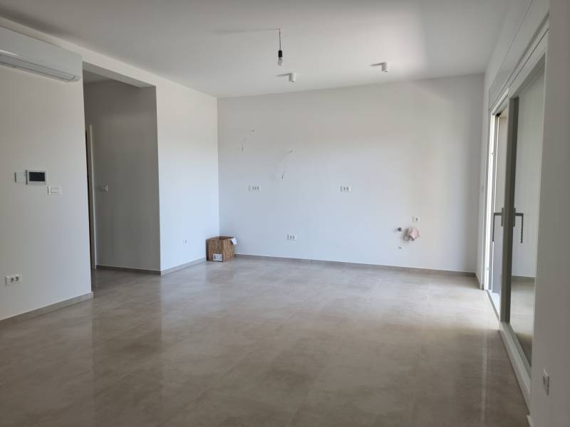 Spacious living room in a 4-room apartment with ceramic flooring and white walls.