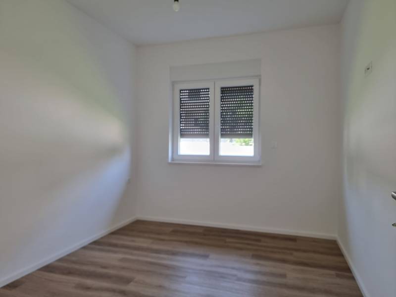 Empty room with wooden floor and a window, 3-room apartment.