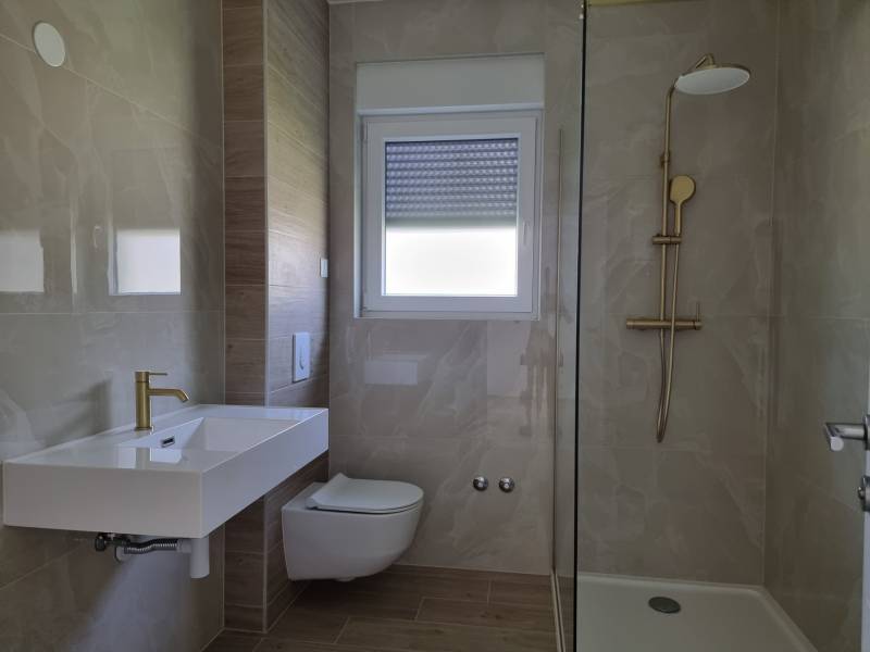 A bathroom in a 3-room apartment with a sink, toilet, and shower.