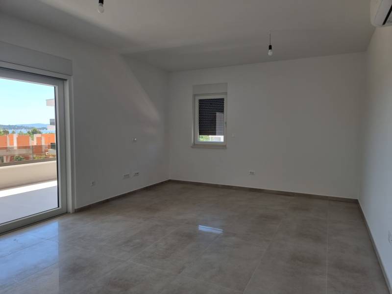 A spacious room of a 4-room apartment with a view to the outside through the balcony doors.