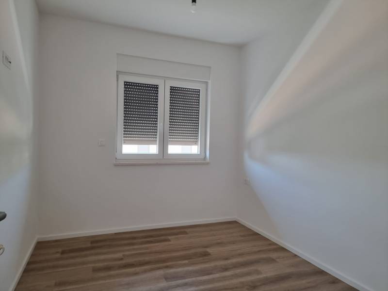 Interior of a 4-room apartment with white walls and wooden flooring.