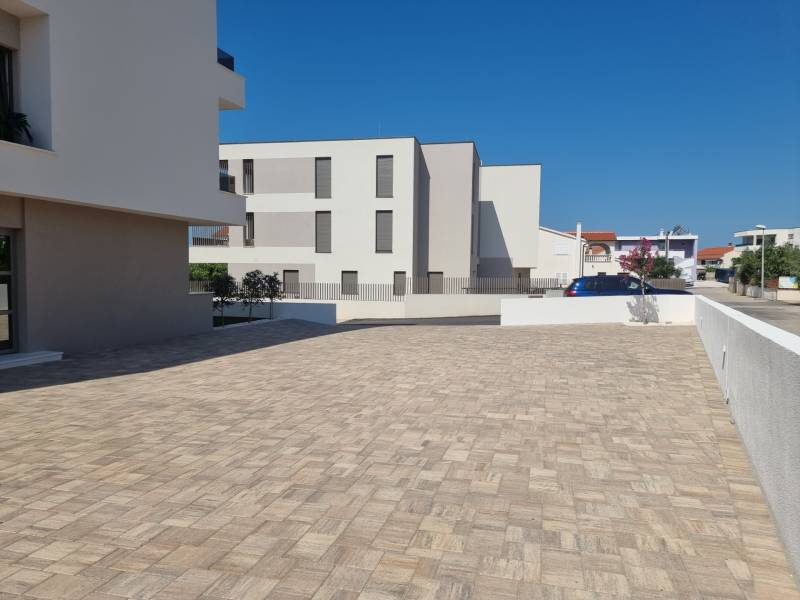 Parking lot at a 4-room apartment in the city of Vodice with a paved surface and clean architecture.