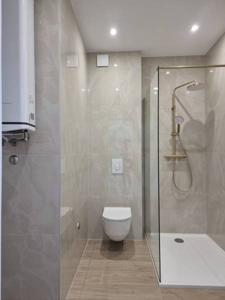 Bathroom in a 4-room apartment with a toilet, shower, and smooth tiles.