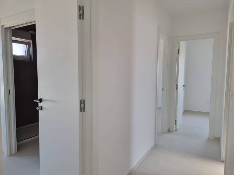 Hallway of a 4-room apartment with white walls and open doors.