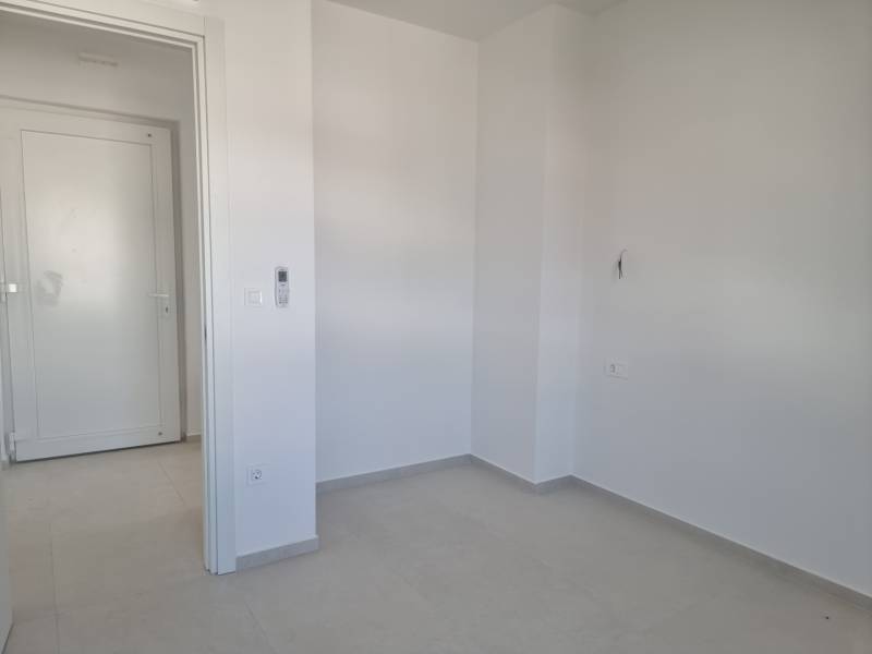 An empty room with white walls and a gray floor in a 4-room apartment.